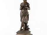 une statue en bronze d'une femme tenant un oiseau sur un piédestal