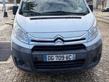 the front of a silver van parked on a cobblestone road