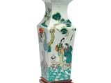 un vase orné d'une peinture, posé sur un socle en bois