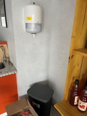 a box of pizza sitting on the floor next to a trash can