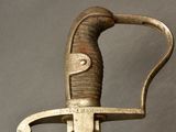 a close up of a sword with a metal handle on a gray background