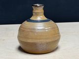 a brown vase sitting on a table with a black background
