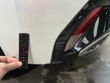 someone is holding a remote control in front of a white car