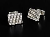 a pair of silver cufflinks on a black surface