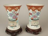 une paire de vases chinois ornés de fleurs, posés sur des socles, sur un fond gris