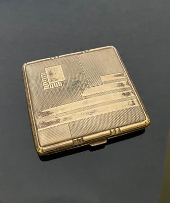 a silver cigarette case sitting on top of a black table