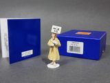 a small figurine of a woman in a yellow dress and a blue box