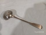 une cuillère en argent posée sur une nappe blanche, le manche vers le bas