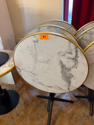 quatre tables rondes en marbre avec des pieds noirs et des finitions dorées