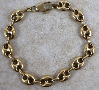 un gros plan d'un bracelet en or posé sur une surface en marbre