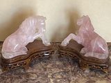 une paire de serre-livres en forme de chevaux en cristal rose posés sur une table en marbre