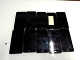 Plusieurs téléphones portables sont alignés sur une table blanche