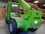 a green crane that is parked inside of a building