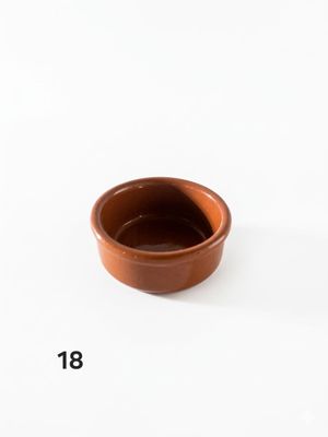 un petit bol marron posé sur une table blanche