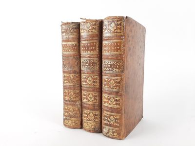 two old books sitting on top of each other on a white surface
