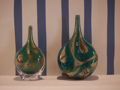 two green vases sitting on a table with blue and white stripes