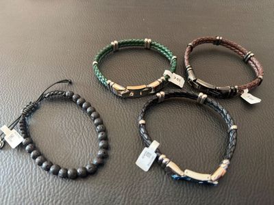trois bracelets ornés d'une croix, posés sur une table