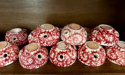 plusieurs vases rouges et blancs posés sur une étagère en bois