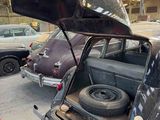 many old cars parked in a garage with the doors open