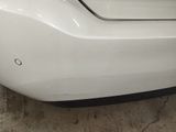 the rear bumper of a white car with a denting dent