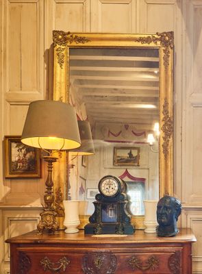 une commode sur laquelle est posée une horloge, devant un miroir