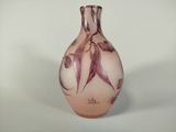un vase rose orné de fleurs violettes, posé sur un fond blanc