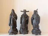 trois statues noires représentant des personnes debout côte à côte sur une table