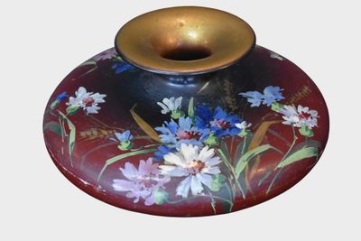 a red vase with blue and white flowers painted on it