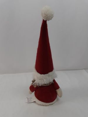 un petit Père Noël en peluche assis sur une surface blanche