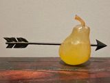 a pear sitting on a table with an arrow stuck in it