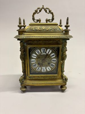 une horloge en or posée sur une surface blanche