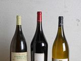 trois bouteilles de vin sont alignées sur une table en bois