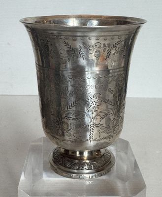 un vase en argent posé sur un socle transparent, sur une table