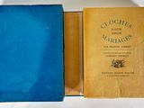 an old book in a blue case sitting on top of a white table