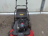 an image of a lawn mower parked in front of a garage