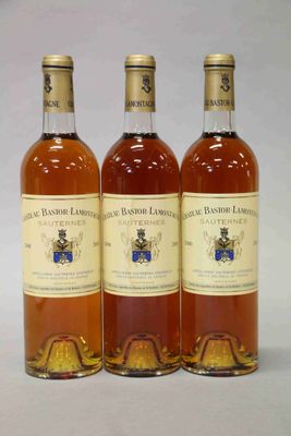 trois bouteilles de vin posées les unes à côté des autres sur une surface blanche