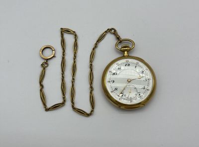 une montre de poche en or et une chaîne posées sur la table