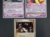 Trois cartes Pokémon sont posées sur une table avec un fond noir.