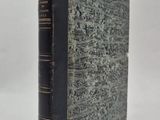 un vieux livre à la couverture noire posé sur une surface blanche
