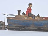 un jouet représentant un homme dans un bateau avec un chien à bord