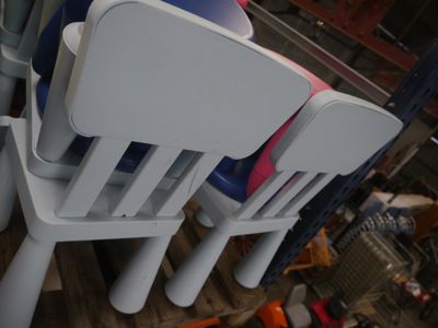 Plusieurs chaises en plastique sont empilées les unes sur les autres dans une pièce