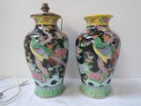 pair of asian vases with birds and flowers on them on a table