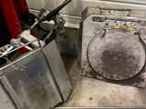 an image of a dirty room with a washing machine and a trash can
