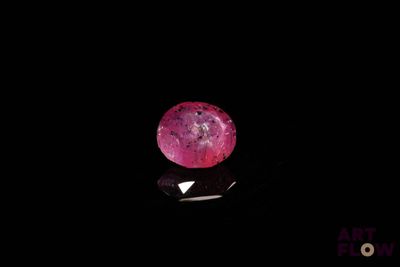 a close up of a pink diamond on a black surface