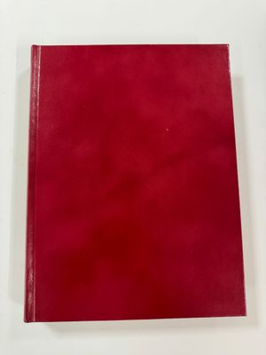 a red book sitting on top of a white table next to a pen
