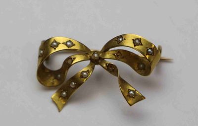 broche en forme de nœud ornée de perles et d'étoiles sur un fond blanc