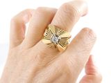 a woman ' s hand holding a gold ring with a diamond on it