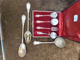 des couverts rangés dans un coffret rouge, posés sur une table à côté d'autres couverts