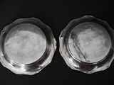 two silver plates sitting on a black surface