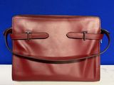 un sac à main en cuir rouge posé sur une table blanche
